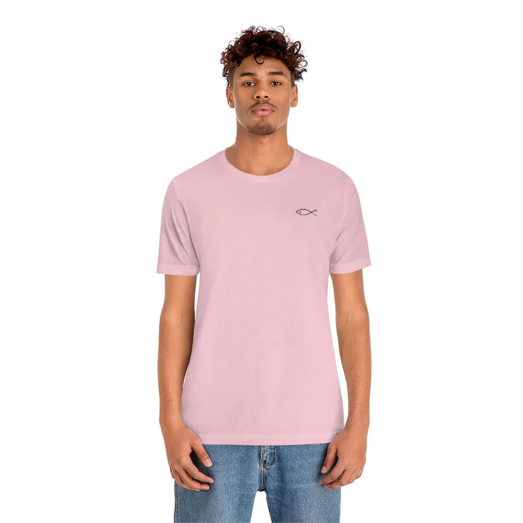 Man wearing light pink Christian fish symbol t-shirt and blue jeans on white background.