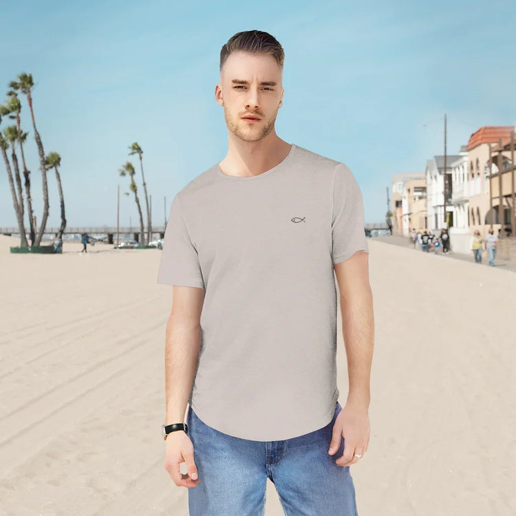 Man wearing light grey Christian fish symbol t-shirt and blue jeans on a sunny beach promenade